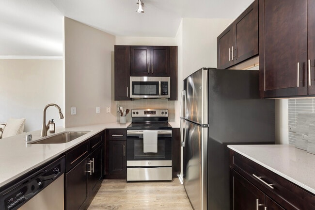 Classic Package I kitchen with stainless steel appliances, tile backsplash, white quartz countertop, espresso cabinetry, and hard surface flooring