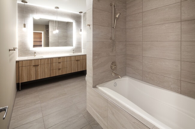 Signature Collection penthouse bath with oak cabinetry and white quartz countertop.