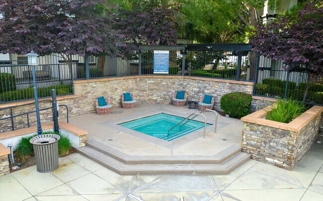 Acogedora zona de jacuzzi con detalles de piedra y asientos tipo lounge