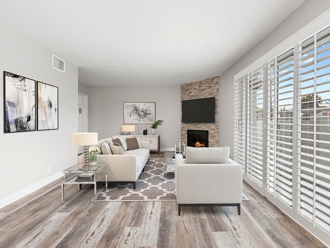 Hardwood floored living room with stone accented fireplace and large exterior windows.