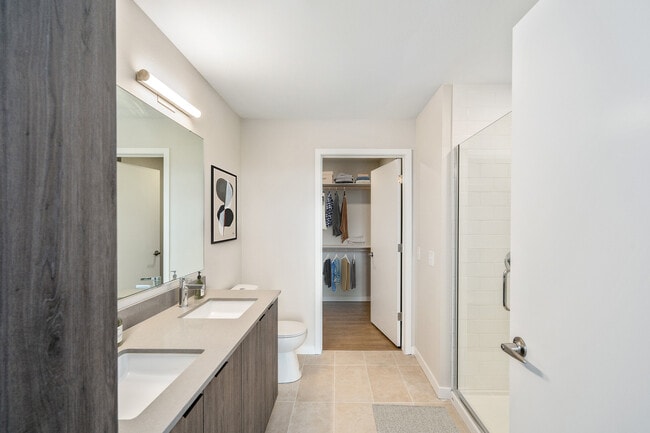 Signature Collection bath with marbled quartz countertop, double vanity, LED lighted vanity mirror, and tile flooring.
