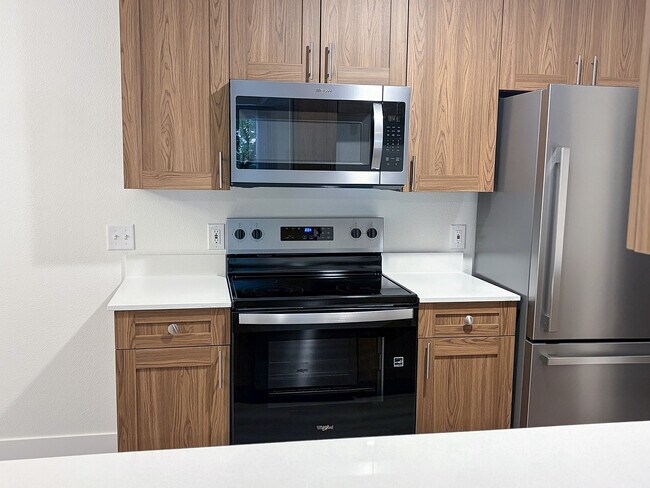Modern stainless steel appliances paired with warm cabinetry create a kitchen you'll love coming home to. - Pinebrook