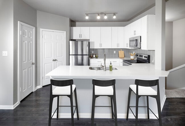 Classic Package II kitchen with stainless steel appliance, white quartz countertop, tile backsplash, white cabinetry, and hard-surface flooring