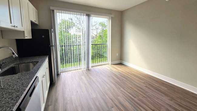 Kitchen and living area with balcony of an available apartment unit at Greenwood Commons Apartments in Delaware, OH.