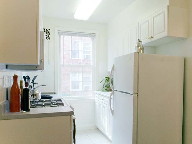 Kitchen with white cabinetry and appliances - eaves Tunlaw Gardens Apartments