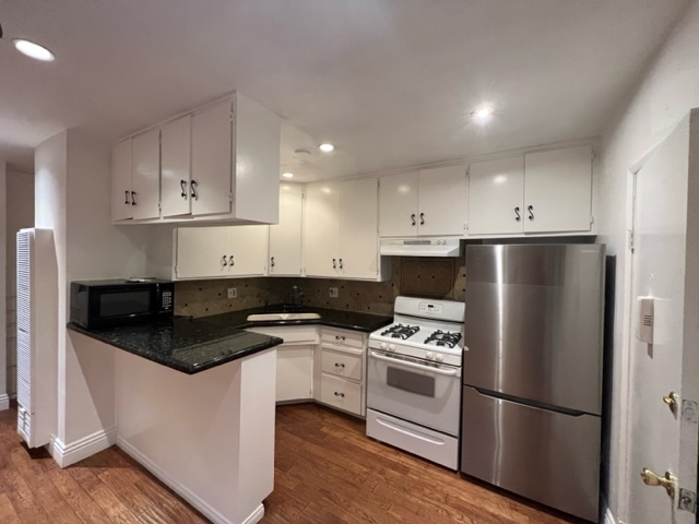 Updated kitchen has stainless steel refrigerator, stove, and lots and lots of cabinet spaces - 5545 1/2 Allott Ave Apartments