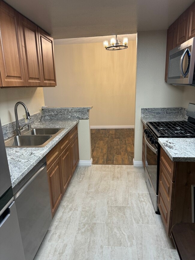 Cocina con electrodomésticos de acero inoxidable, encimeras de mármol y azulejos de porcelana. - 10824 Palms Blvd Unidad 3