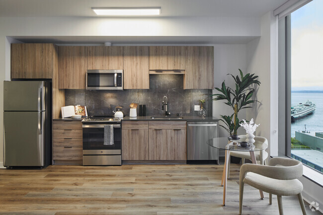 Apartment kitchen with stainless steel appliances, quartz countertops and wood-style flooring. - Griffis Seattle Waterfront Rental