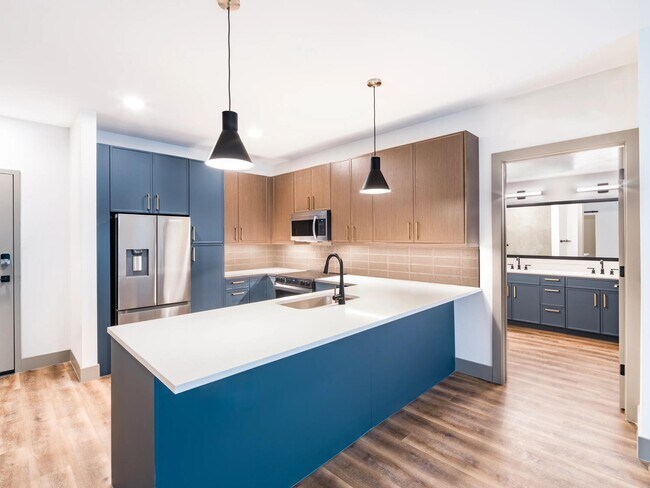 A clean, contemporary kitchen with bold cabinetry, generous counter space, and designer lighting. - Modera Chandler