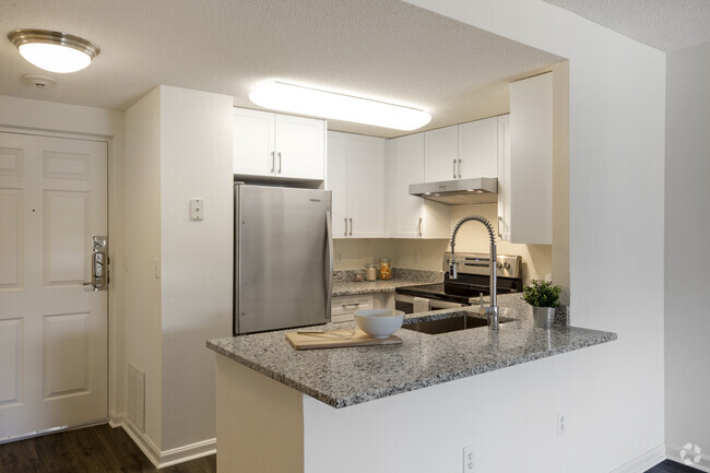 Renovated Package III kitchen with white cabinetry, grey granite countertops, stainless steel appliances, and hard surface flooring - eaves Washingtonian Center Rental