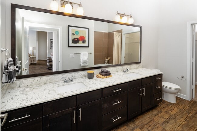 Primary bath with espresso cabinetry, granite countertops, and hard-surface vinyl plank flooring