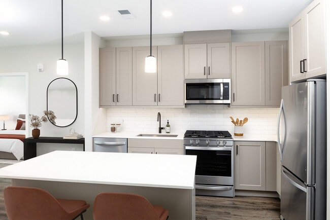 Upgrade Collection kitchen with stainless steel appliances, quartz countertops, tile backsplash, grey cabinetry, and hard-surface flooring