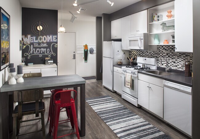 Classic Package I kitchen with white appliances, dark laminate countertops, white cabinetry, tile backsplash, and hard surface flooring