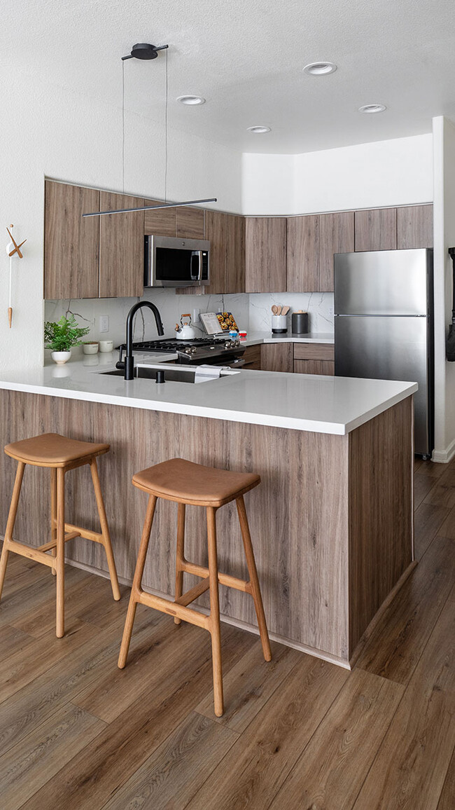 Apartment Kitchen with Stainless Steel Appliances, quartz counters and wood floors. - Griffis Mission Valley Apartments