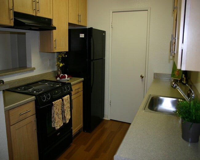 Kitchen with grey laminate countertop, black appliances, oak cabinetry and hard surface flooring