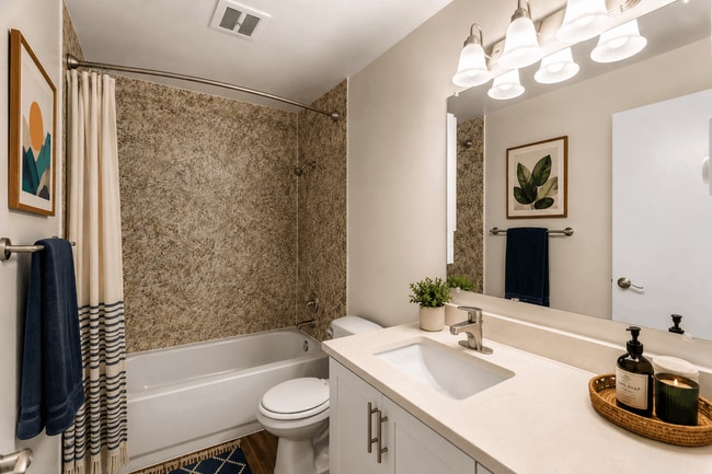 A bright, stylish bathroom with modern finishes and a convenient tub and shower combination at Chambers Pointe Apartments.