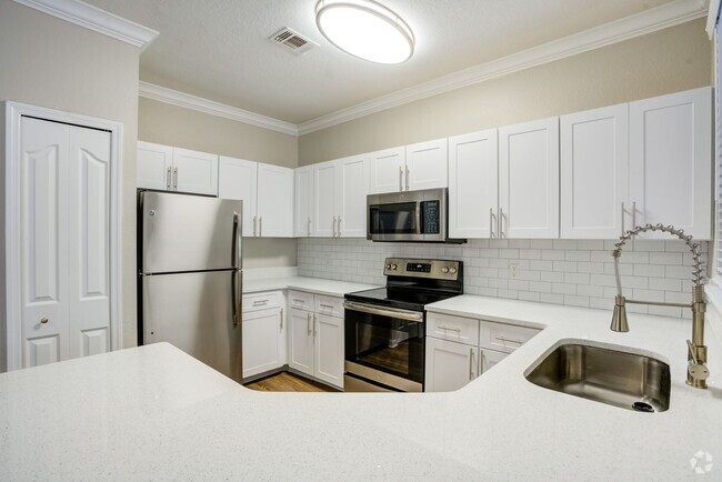 Image of a kitchen with wrap around quartz counters and a ceramic backsplash. - Amara at Metro West Rental