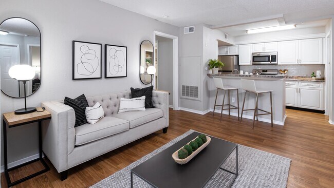 Disfrute de la sensación acogedora de esta sala de estar de concepto abierto con pisos estilo madera, acabados modernos y una conexión perfecta con la cocina, perfecta para recibir invitados o relajarse. - The Oasis at 1800