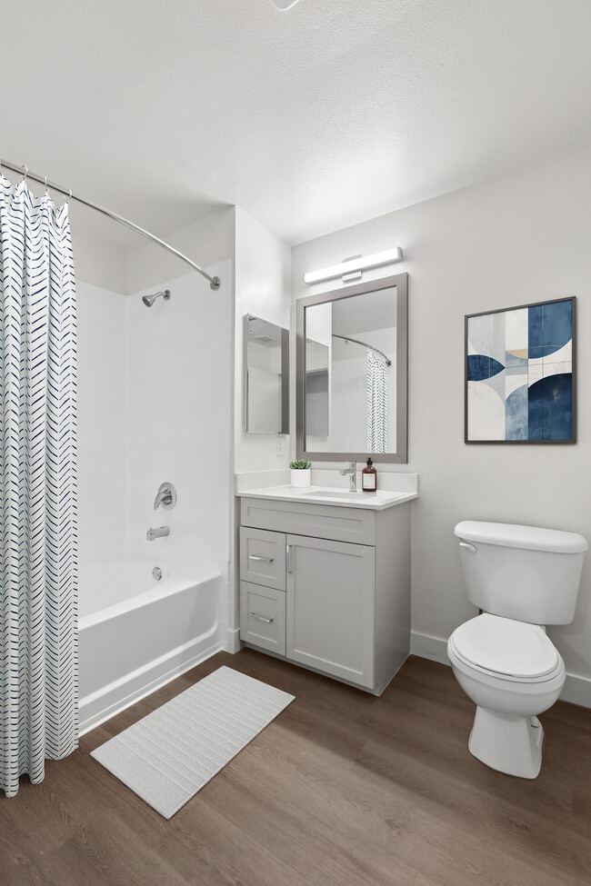 Renovated Package II bath grey cabinetry, white quartz countertops, and hard surface flooring - Avalon at Cahill Park