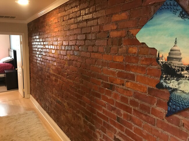 Exposed brick and hardwood continue through the hallway - 712 13th Street Northeast Townhome