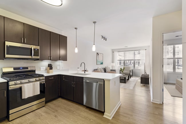 Renovated Package I kitchen with stainless steel appliances, white quartz countertops, espresso cabinetry, beige tile backsplash, and hard surface flooring