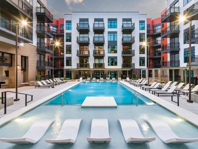 Resort-style pool courtyard with in-water loungers, sundeck seating, and private balconies surrounding the space.