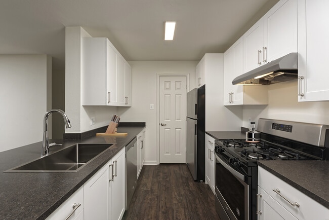 Renovated Package II kitchen with white cabinetry, dark grey laminate countertops, and stainless steel appliances, and hard surface flooring