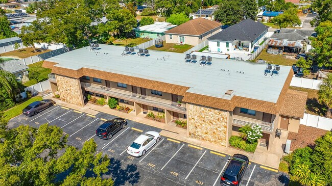 Aerial view of a charming two-story apartment building with ample parking and lush green surroundings.
