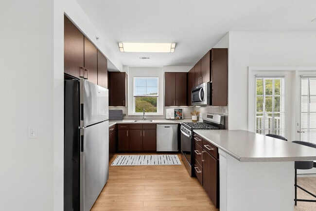 Updated Finishes kitchen with stainless steel appliances, espresso cabinetry, tile backsplash, laminate countertops, and hard surface flooring - Avalon Bloomingdale