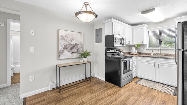 Discover a classic dining space with wood-style floors and a stylish overhead lighting fixture, thoughtfully designed to connect the kitchen and living room seamlessly.