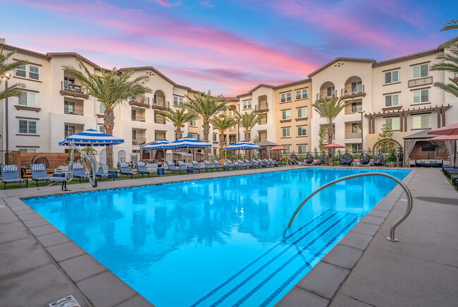 Resort-style pool with lounge seating and personal cabanas with TV’s. - LIVIA at Scripps Ranch Apartments