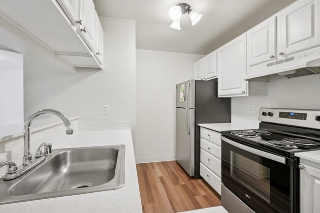 Classic Package III kitchen with stainless steel appliances, white cabinetry, laminate countertops, and hard surface flooring