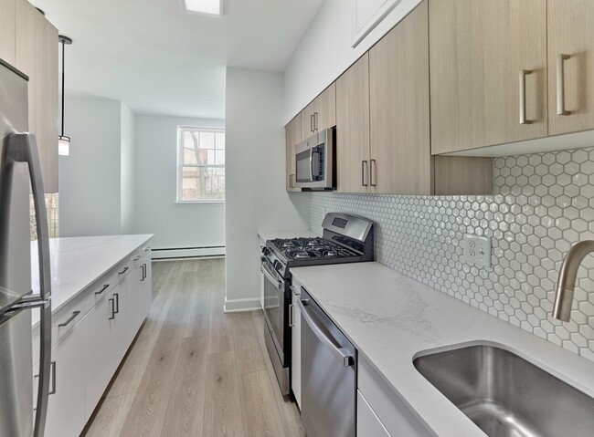 Modern galley-style kitchen with quartz countertops and stainless steel appliances at Crestwood Apartments in Wayne, PA
