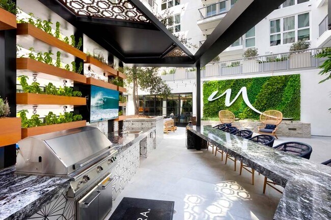 One of two lushly-landscaped courtyards with outdoor kitchen, bar seating, and TV