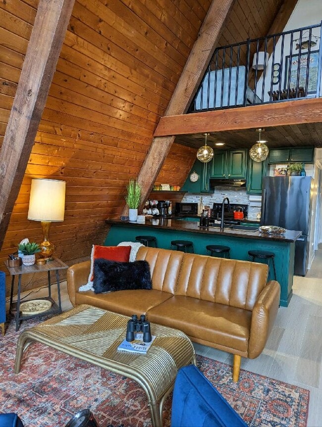 Una acogedora sala de estar con un sofá de cuero color caramelo, iluminación cálida y vista a la cocina. - 2406 Crockett Cir