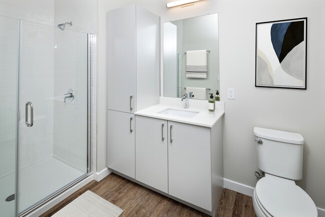 Bath with white quartz countertop, light grey cabinetry, and hard surface flooring