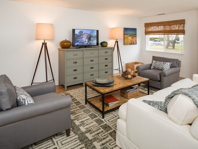 Furnished living room with a sofa, lounge chairs, coffee table, and high ceiling at Yardley Crossing