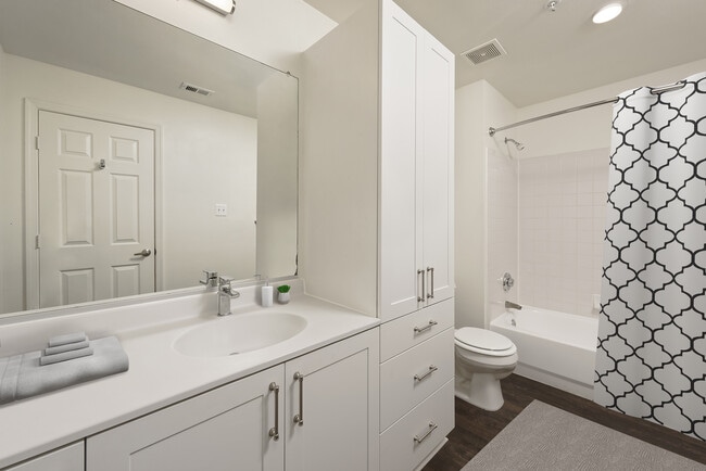 Renovated Package II bath with white cultured marble countertops, white cabinetry, and hard surface flooring