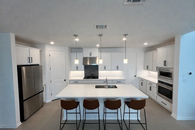 Spacious modern kitchen with large island, 5-burner gas cooktop, and stainless steel appliances. - 517 Moonlit Stream Pass