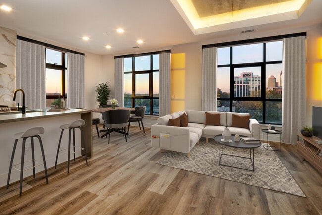 Kitchen, living, and dining areas with hard surface flooring throughout and floor-to-ceiling windows