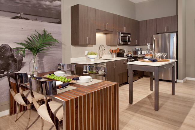 Dining area and open concept kitchen with quartz stone countertops, stainless-steel appliances, kitchen island and hard surface flooring - Avalon Potomac Yard Apartments