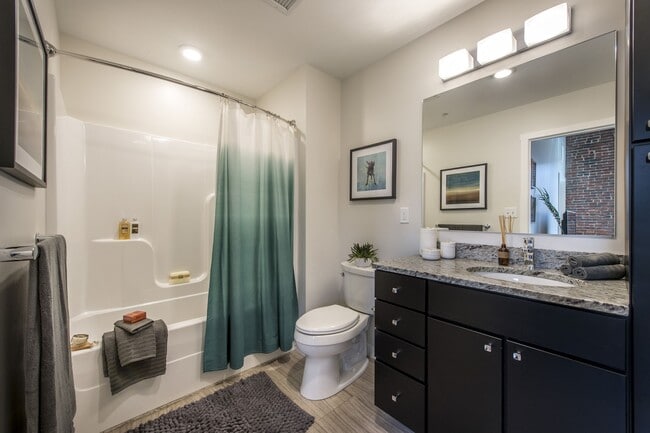 Baño de apartamento reformado con moderno lavabo, bañera y grifería contemporánea.