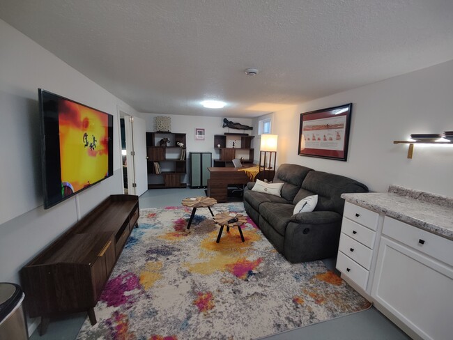 Combination living room/office with reclining sofa, 65" smart TV, and direct wired ethernet at the d - 2913 Clover St Apartamentos Unidad B