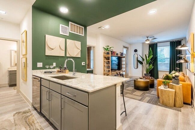 A modern kitchen with a green wall and a marble countertop.
