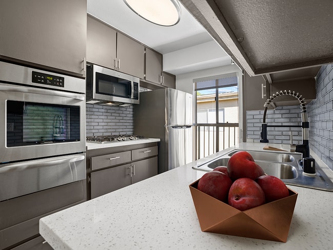 Blue tiled kitchen with stainless steel oven, microwave, fridge, and fixtures.