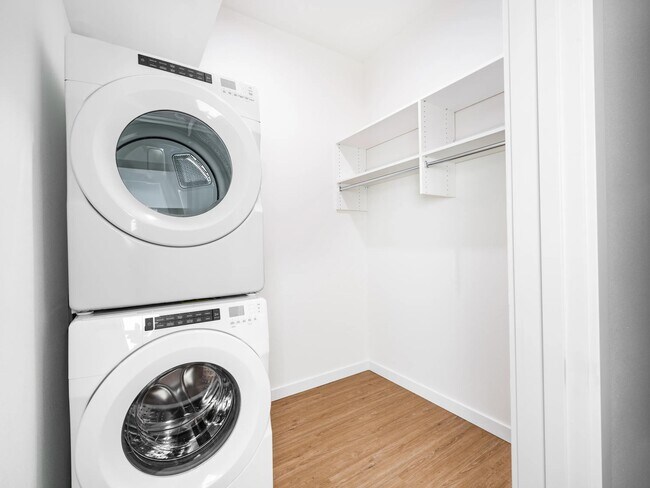 In-home laundry area with stacked washer and dryer alongside a spacious closet, designed for organized storage and everyday convenience.