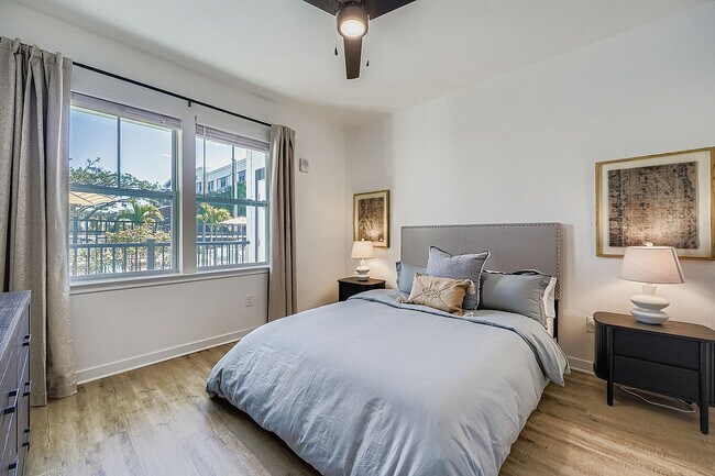 Inviting bedroom with contemporary decor, featuring a large window with a lush outdoor view, a plush bed with elegant pillows, and warm ambient lighting.