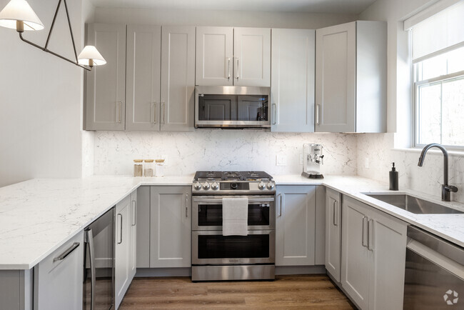 Signature Collection kitchen with stainless steel appliances, white quartz countertop, grey cabinetry, white quartz backsplash, and hard surface flooring - Avalon Princeton Circle Rental