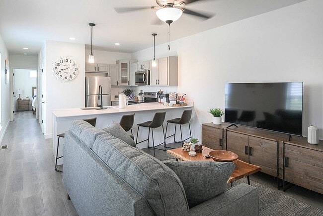 Modern open-concept living space with a stylish kitchen, cozy sofa, chic dining area, and elegant decor. - Highland Park Apartments