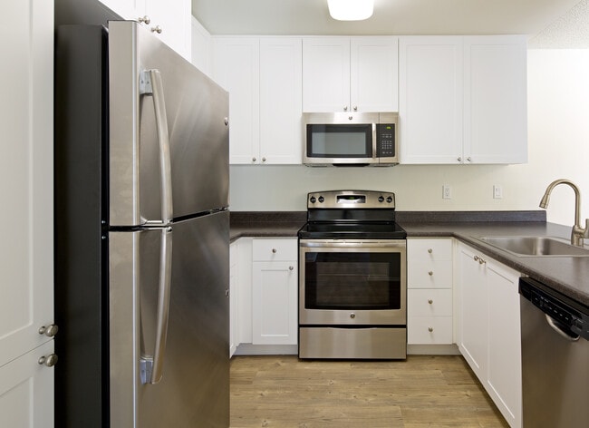 Renovated Package I kitchen with stainless steel appliances, white cabinetry, laminate countertops, and hard-surface flooring